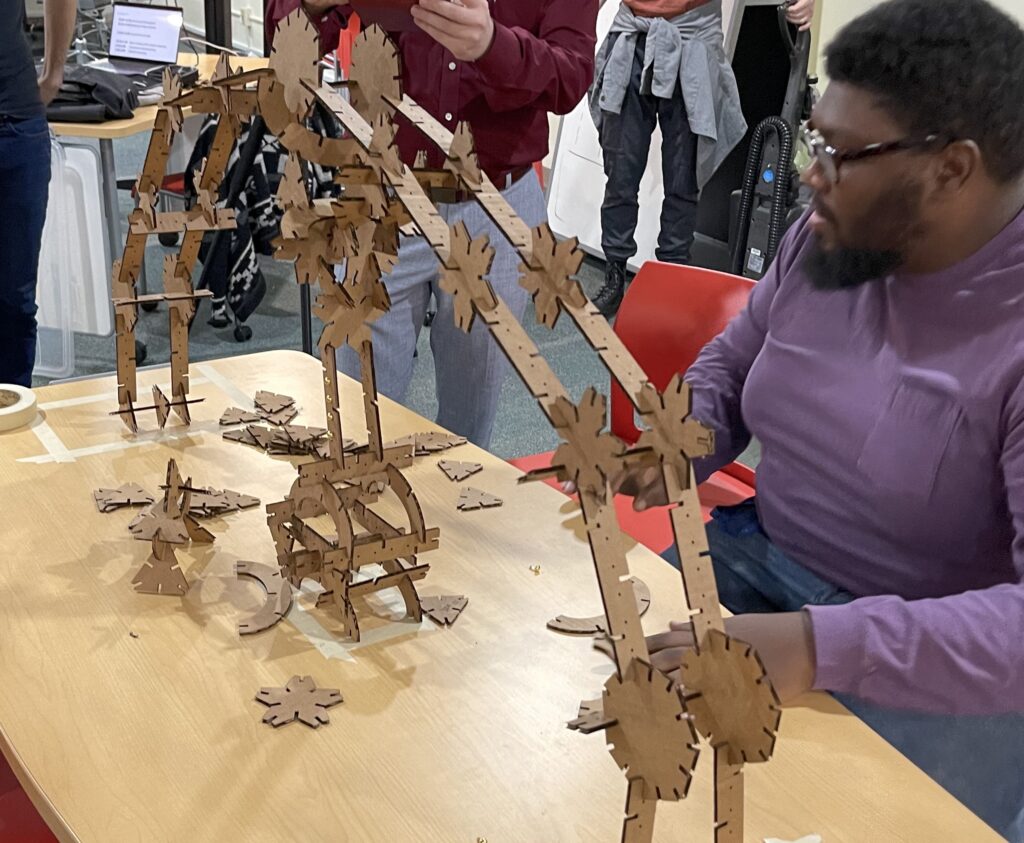 student making a bridge out of pieces of wood burned from a laser cutter