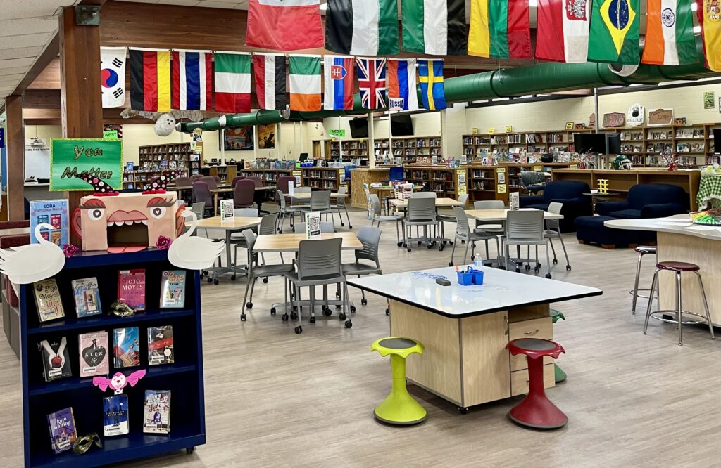 teen space in school library with national flags on the ceiling and several small group work spaces